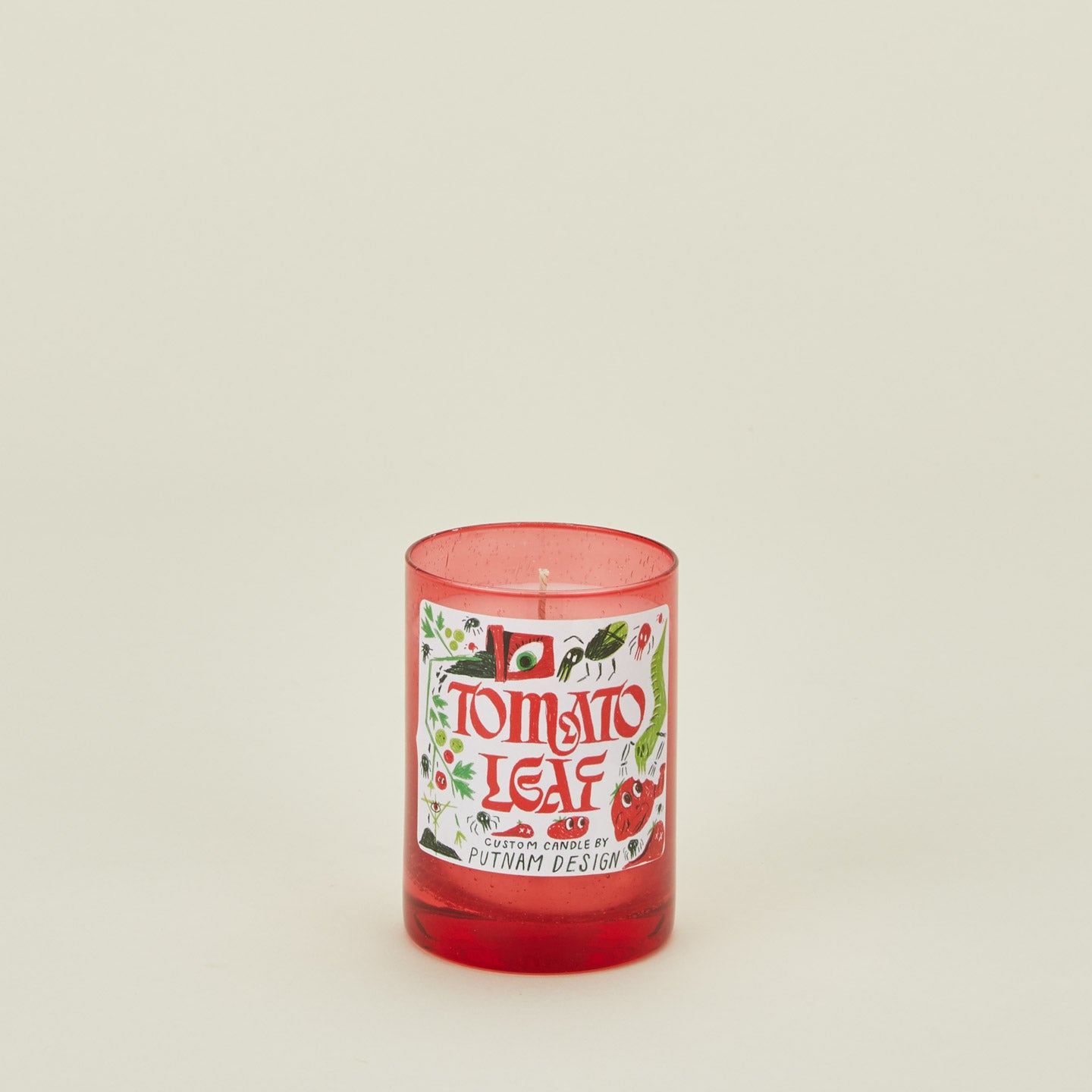 Candle with a 'Tomato Leaf' label on a beige background