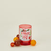Candle with a tomato leaf label surrounded by tomatoes on a beige background