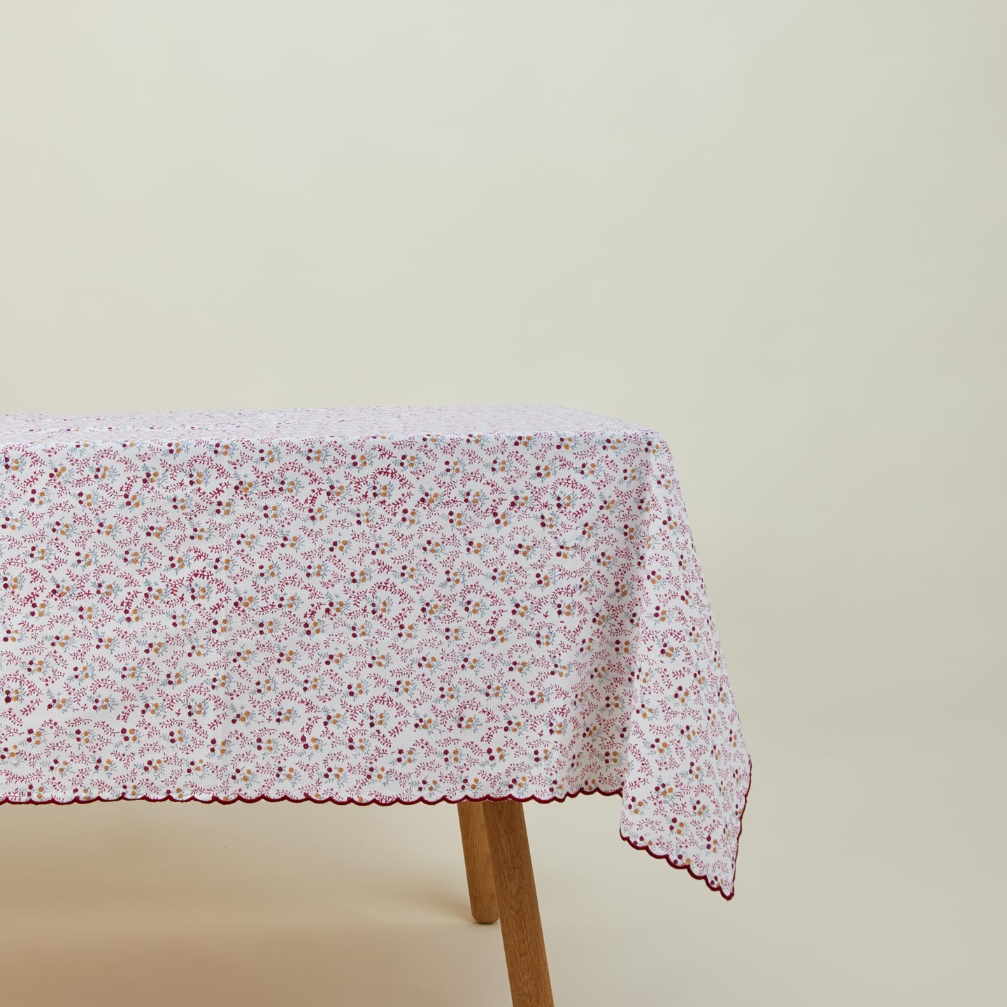 Little flowers rectangular tablecloth in maroon on table.