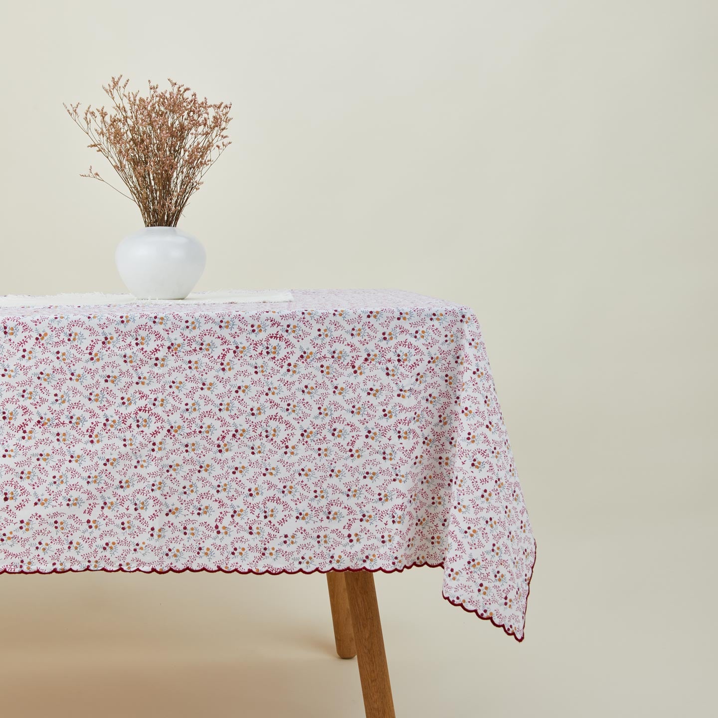 Little flowers rectangular tablecloth in maroon on table with flowers in vase.