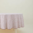 Round little flowers tablecloth in maroon on table.