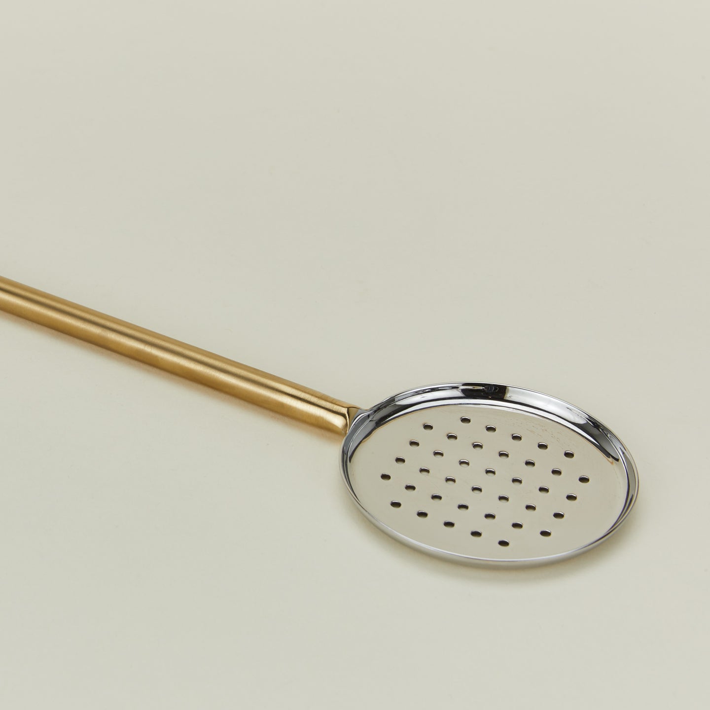 Close up of simple metal flat slotted spoon in brass.