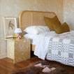 Bedroom with a bed featuring a wicker headboard, nightstand, and decorative items.