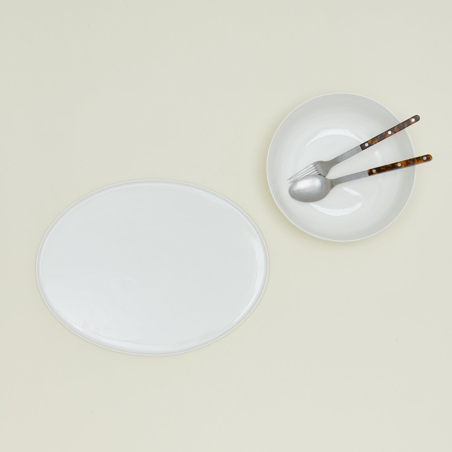 Overhead view of simple porcelain serving set with utensils