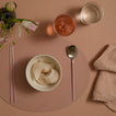 Dinner setting with dumplings, a bowl, spoon, and chopsticks on a pink placemat.