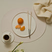 Table setting with a plate of fruit, coffee, and chopsticks on a beige surface.
