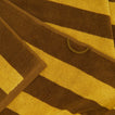 A close up of a striped mustard and bronze terry bath towel with a hanging loop.