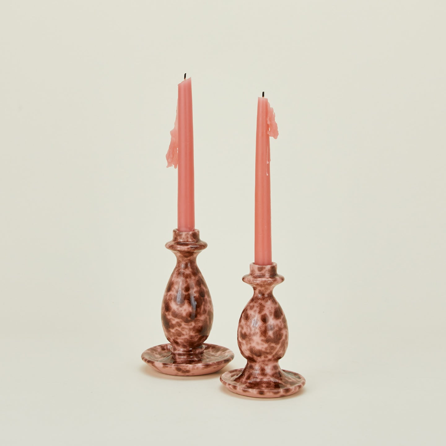 Large and small candlestick holders in blush and terracotta with candles