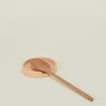 A blush stoneware spoon rest with a wooden spoon.
