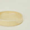 A close up of a butter stoneware spoon rest.