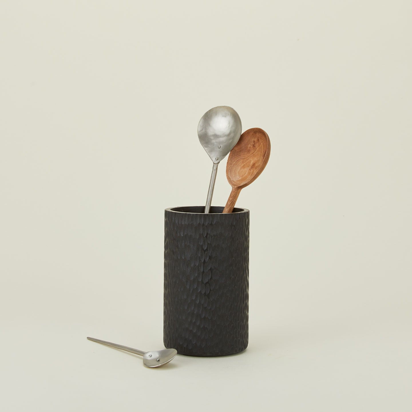 Forged pewter spoons and wooden spoon in black wood canister.