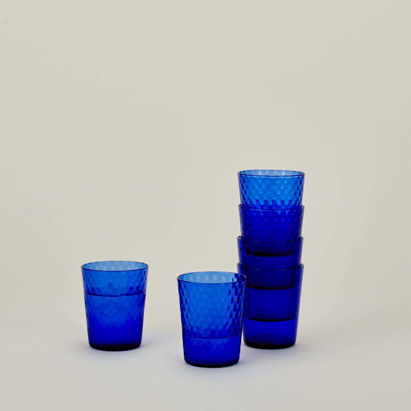 Set of 6 Veneziano Tumblers in Cobalt, stacked, with water.