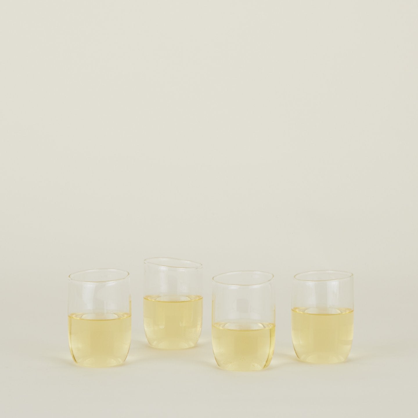 Four clear Boreal Tumblers in Medium size filled with white wine.