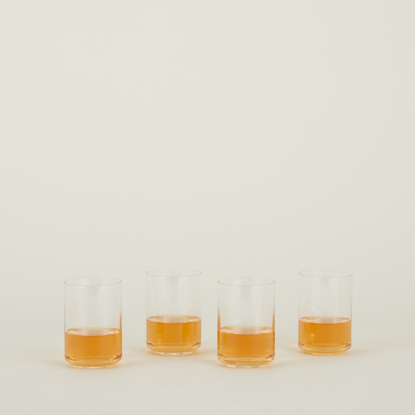 Four clear Simple Glasses in Tumbler size filled with sparkling wine.
