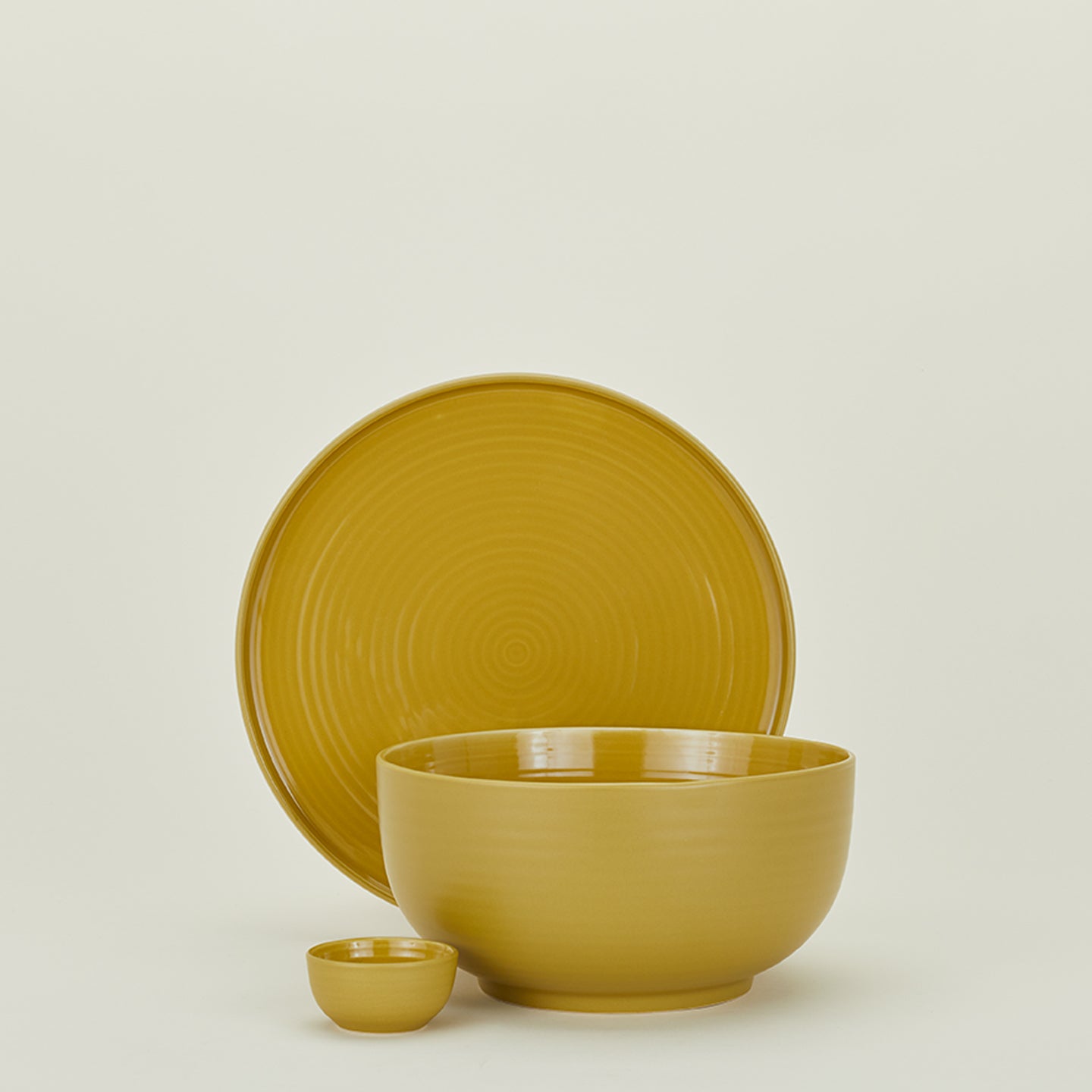 Group of Essential serving pieces in Mustard including bowl, platter and extra small bowl.